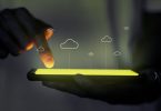 Finger with touch screen phone with cloud and wifi images overlaid on top