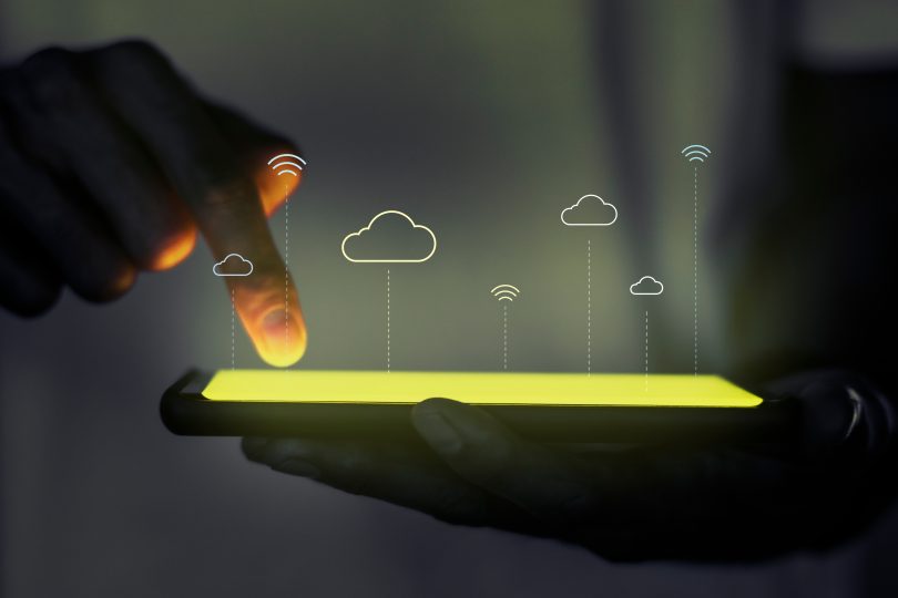 Finger with touch screen phone with cloud and wifi images overlaid on top