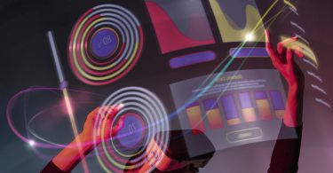 Picture of woman with Augmented Reality (AR) headset on in black clothes with grey and black background and heads up display that's a purple and red hologram