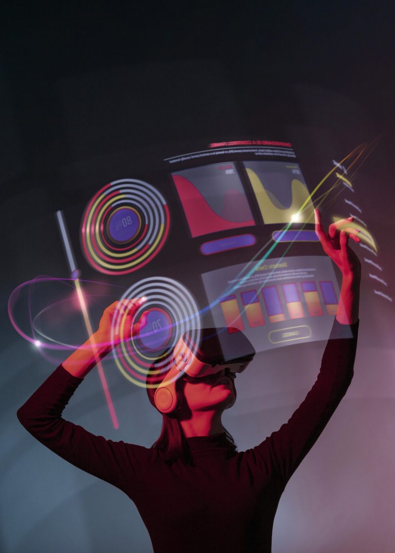 Picture of woman with Augmented Reality (AR) headset on in black clothes with grey and black background and heads up display that's a purple and red hologram
