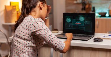 Angry hacker woman because of access denied while trying to attack government firewall. Programmer writing a dangerous malware for cyber attacks using performance laptop during midnight.