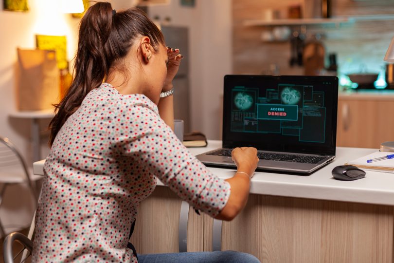 Angry hacker woman because of access denied while trying to attack government firewall. Programmer writing a dangerous malware for cyber attacks using performance laptop during midnight.