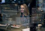 Picture of white woman with glasses coding with heads up display of FOSS code user interface overlaid