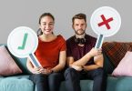 Cheerful couple holding vote icon sitting on a couch
