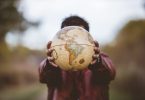 Closeup shot of a male wearing a leather jacket holding a globe in front of him