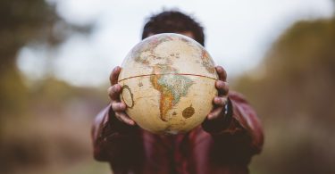 Closeup shot of a male wearing a leather jacket holding a globe in front of him